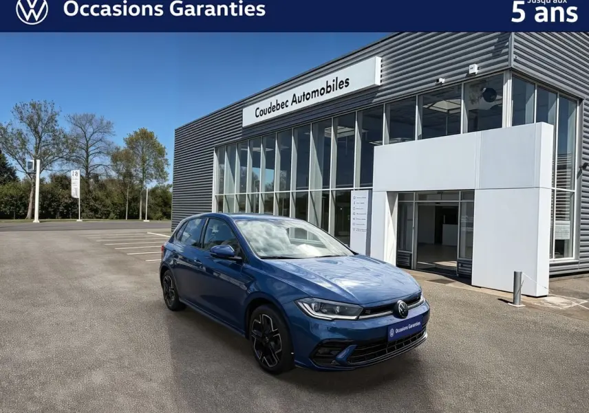 Vue 3/4 avant gauche d'une Volkswagen Polo 2025 bleu récif métallisé avec toit noir devant un concessionnaire.