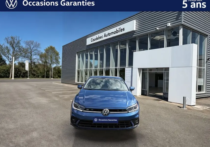 Volkswagen Polo bleu métallisé vue de face, avec calandre noire et logo VW bien visible, devant un bâtiment moderne.