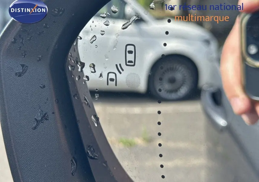 Rétroviseur gauche d'un Renault Austral gris schiste métal avec toit noir, montrant l'alerte d'angle mort et reflet d'une main.