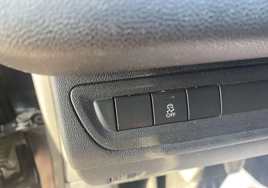 Gros plan sur le bouton de désactivation de l'ESP dans l'habitacle d'une Peugeot 208 noire de 2016.