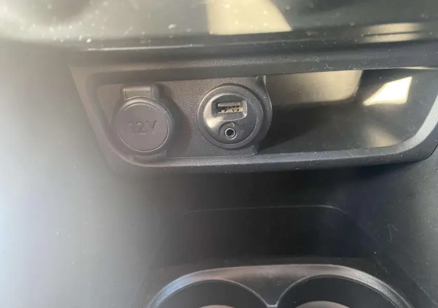 Prise 12V et port USB en gros plan dans l'habitacle d'une Peugeot 208 noire 2016 version Active+ GPS.