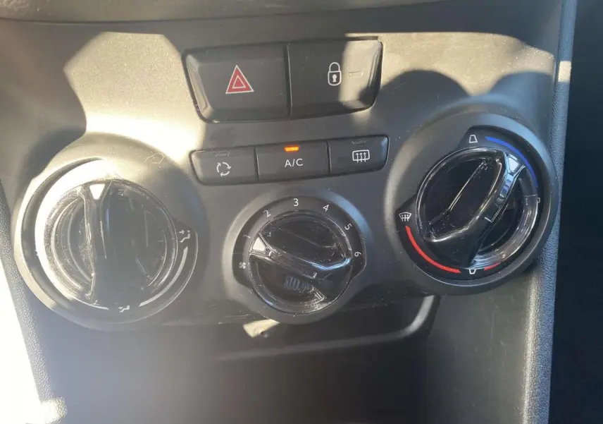 Commandes de climatisation et verrouillage central d'une Peugeot 208 noire, vue rapprochée du tableau de bord.