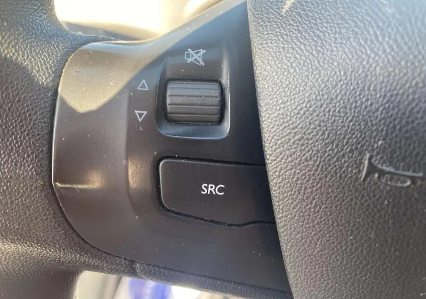 Gros plan sur les commandes audio au volant d'une Peugeot 208 noire, version Active+ GPS de 2016.