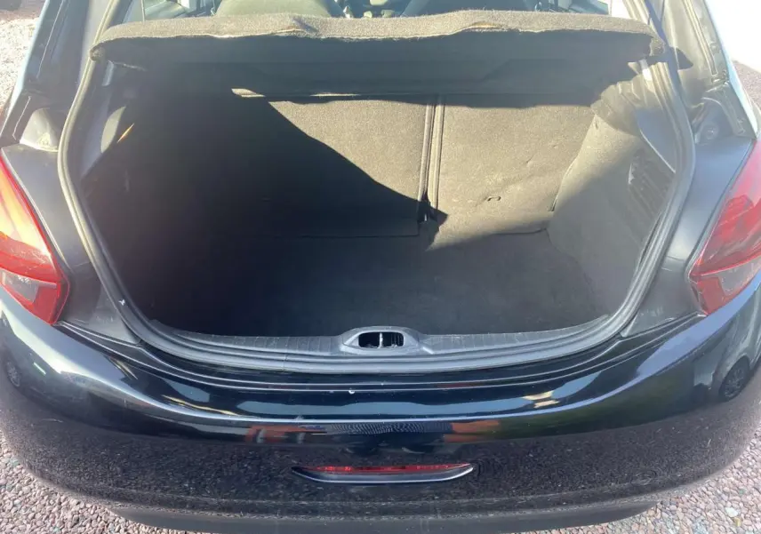 Coffre ouvert en vue arrière d'une Peugeot 208 noire de 2016, montrant l'espace de chargement vide.