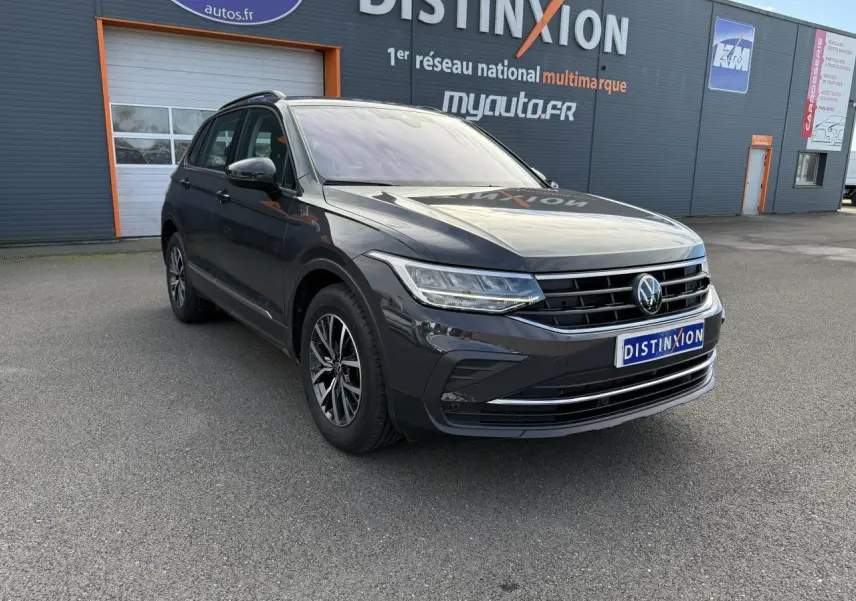 Volkswagen Tiguan gris Urano en 3/4 avant droit, avec jantes alliage et calandre chromée visible.