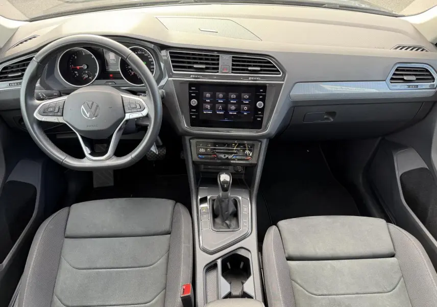 Vue intérieure frontale du Volkswagen Tiguan 2023 montrant le volant multifonction, écran tactile central et console avec levier de boîte auto.