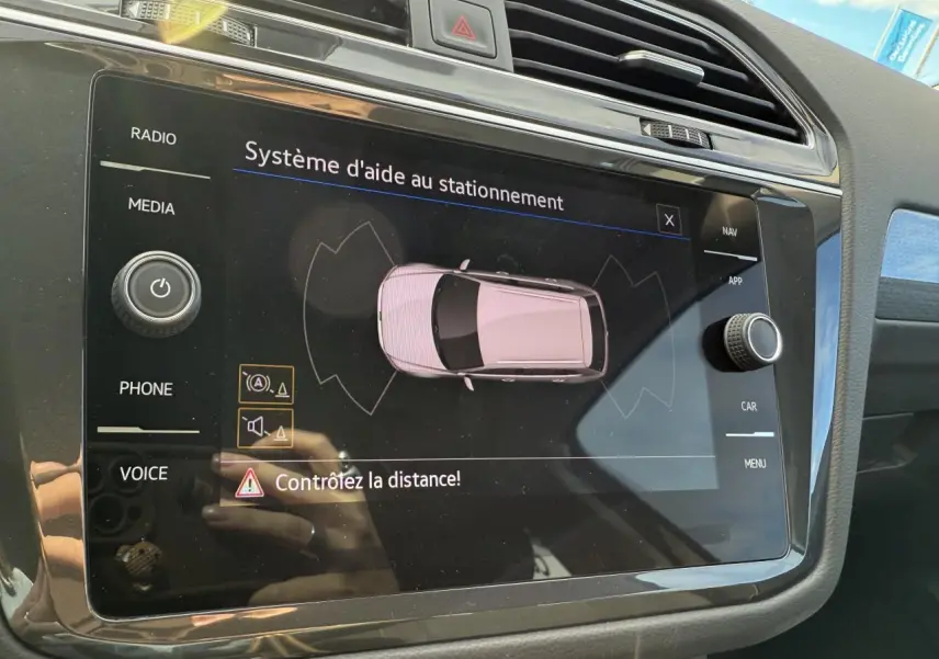 Écran tactile du système d'aide au stationnement dans l'habitacle du Volkswagen Tiguan gris Urano, vue rapprochée.