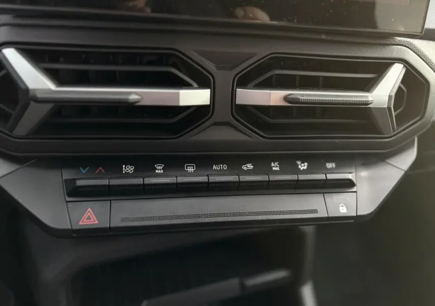 Détail des commandes de climatisation et des aérateurs noirs avec inserts argentés dans l'habitacle du Dacia Duster 2024.