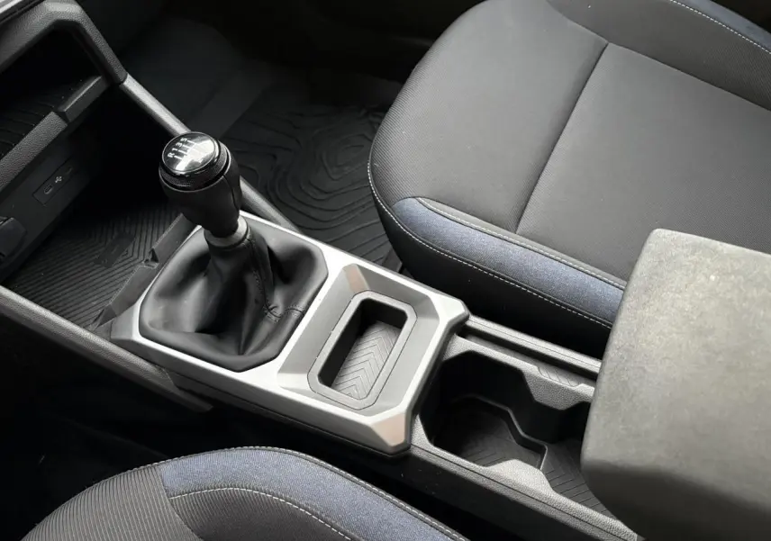 Vue rapprochée de la console centrale et levier de vitesses manuel du Dacia Duster 2024 avec sellerie Denim bleu et noire.