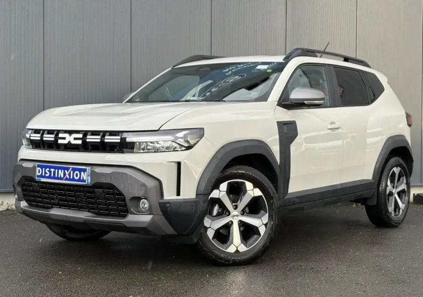 Vue 3/4 avant droite du Dacia Duster 2024 beige Sandstone avec barres de toit noires et jantes alliage 18 pouces.