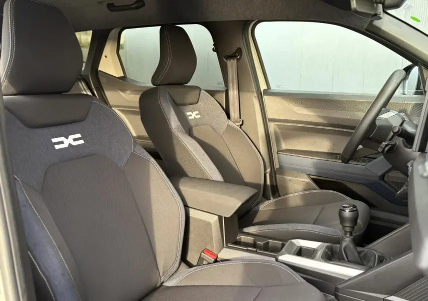 Vue intérieure côté droit du Dacia Duster 2024, sièges Denim avec logo Dacia, volant soft feel et levier de vitesses manuel.