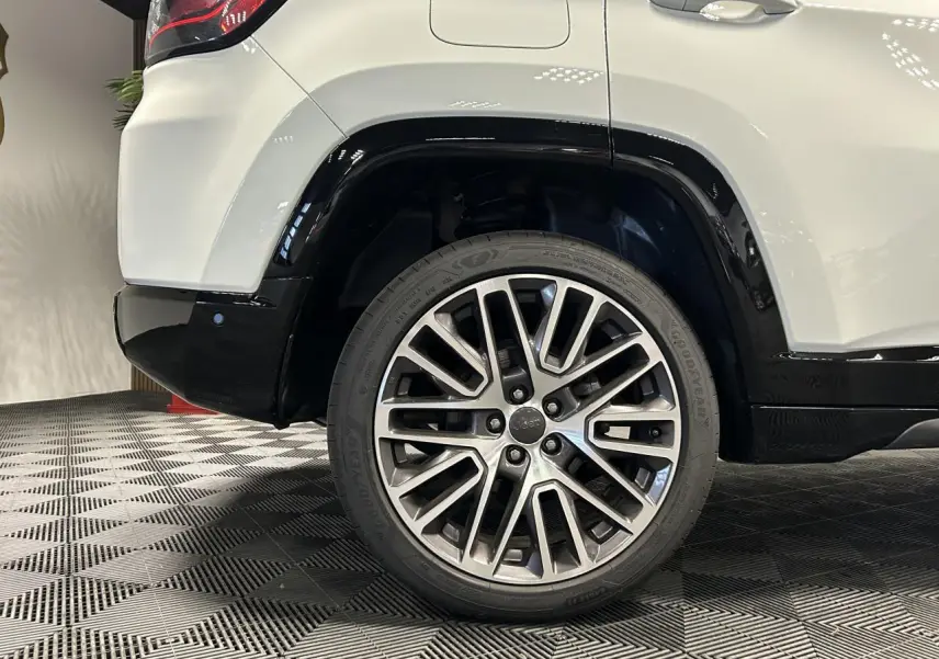 Gros plan sur la roue arrière droite du Jeep Compass blanc avec jante alliage 19'' Diamond et bas de caisse noir brillant.