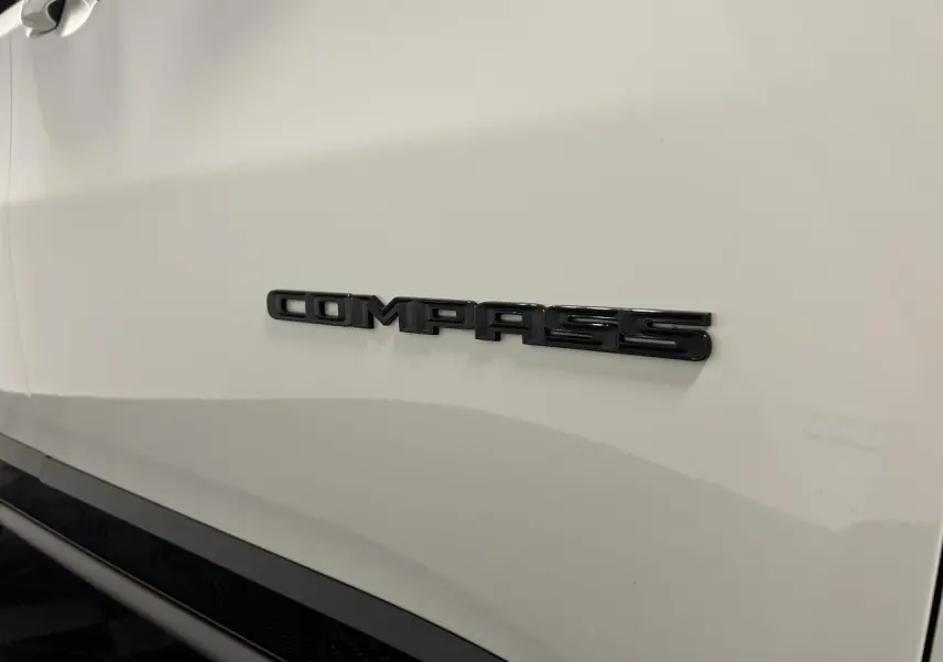 Gros plan sur l’inscription Compass en noir sur la portière blanche d’un Jeep Compass 2024.