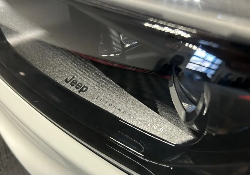 Gros plan sur le phare avant LED du Jeep Compass blanc avec inscription "Jeep Performance LED" visible.