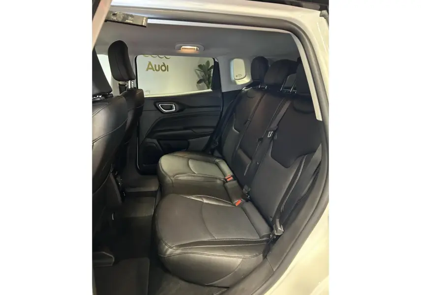 Vue intérieure côté droit sur la banquette arrière en cuir noir du Jeep Compass blanc avec surpiqûres grises.
