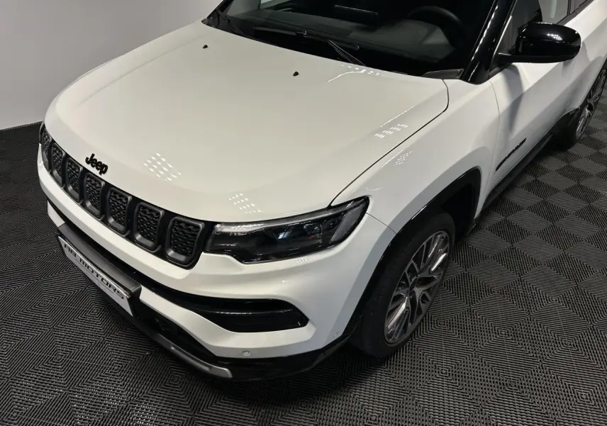 Vue 3/4 avant droit du Jeep Compass blanc avec toit noir et jantes alliage 19 pouces sur sol intérieur.