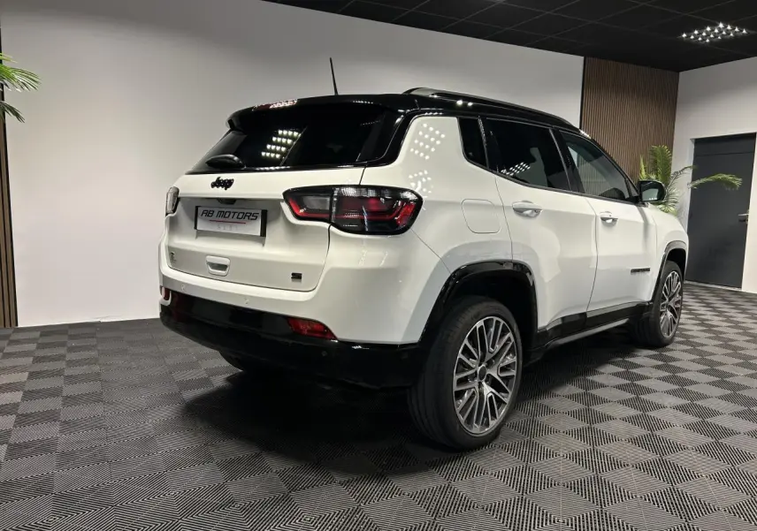 Jeep Compass blanc vue 3/4 arrière droit avec toit noir et jantes alliage 19 pouces en intérieur showroom.