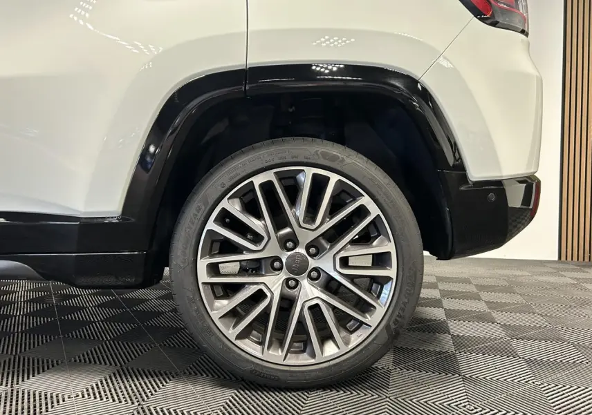 Gros plan sur la roue arrière droite du Jeep Compass blanc avec jante alliage 19 pouces et bas de caisse noir brillant.