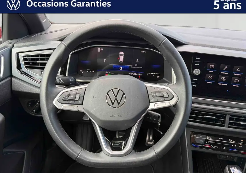 Vue intérieure centrée sur le volant cuir multifonctions et le tableau de bord digital de la Volkswagen Polo rouge 2025.