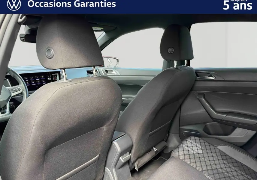 Vue intérieure arrière montrant les sièges avant et la banquette arrière d'une Volkswagen Polo 2025 avec sellerie tissu gris.