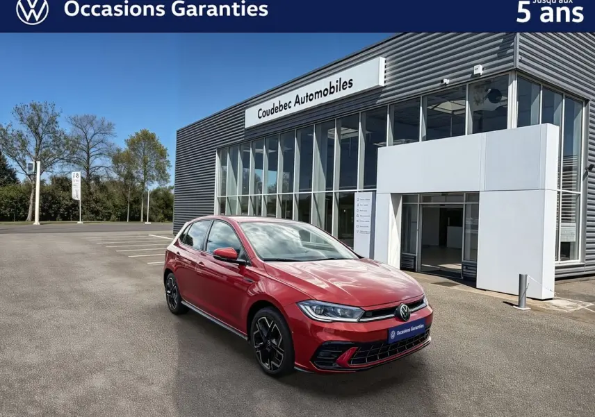 Volkswagen Polo rouge métallisée vue 3/4 avant droit, avec jantes alliage noir et calandre sportive, devant un showroom.