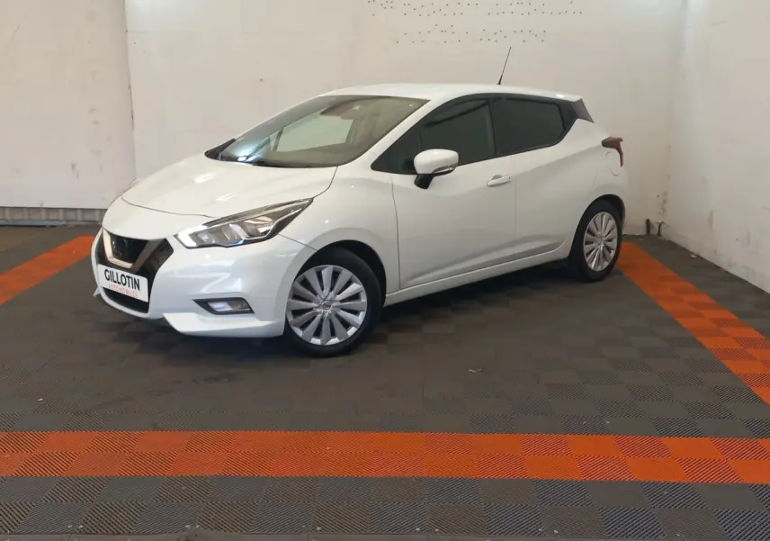 Nissan Micra blanche vue 3/4 avant droit, avec jantes alliage et feux avant distinctifs en intérieur neutre.