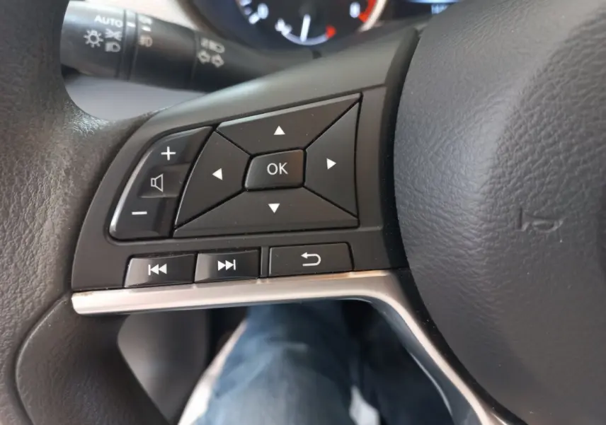 Gros plan sur les commandes multifonctions du volant noir de la Nissan Micra IG-T 90 Business Edition, intérieur visible.