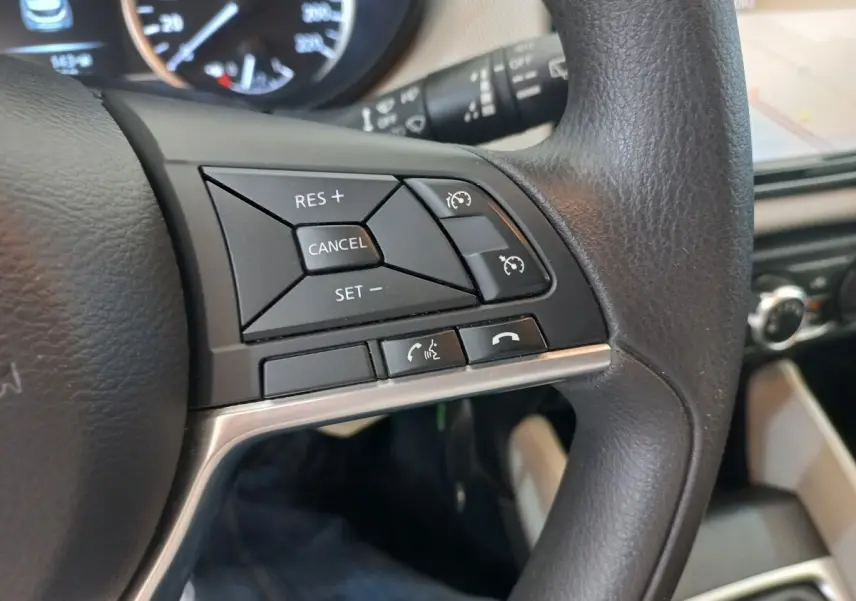 Gros plan sur le côté droit du volant noir de la Nissan Micra blanc, avec commandes du régulateur de vitesse et téléphone.