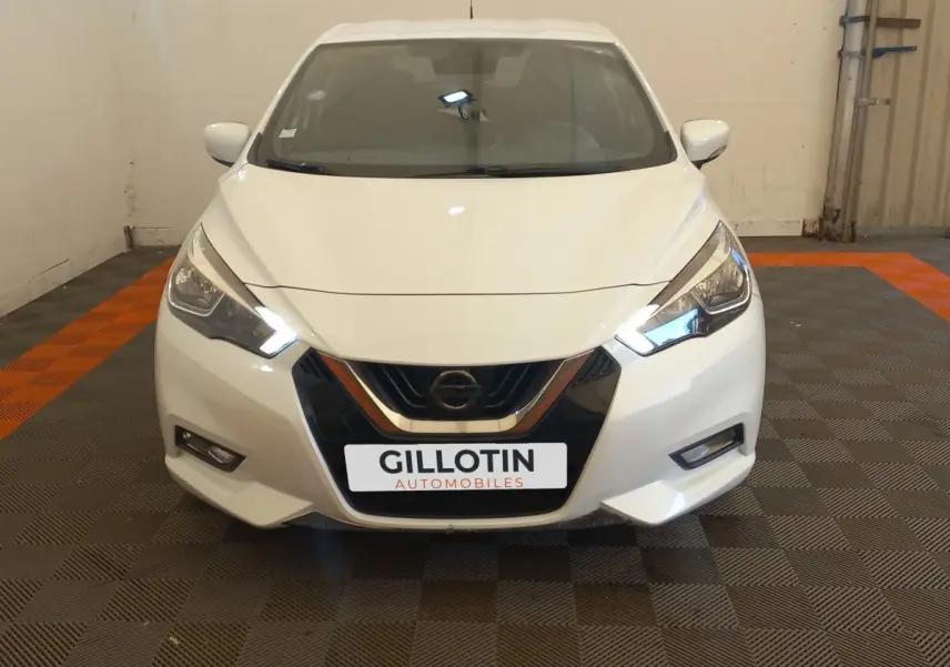 Vue frontale d'une Nissan Micra blanche avec phares LED allumés et calandre noire brillante.