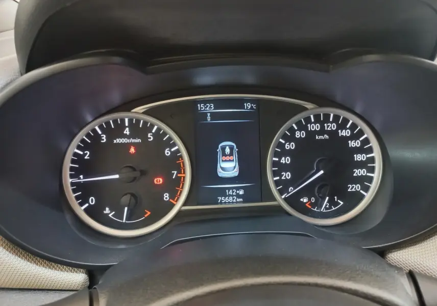Vue rapprochée du tableau de bord de la Nissan Micra blanc, affichant compte-tours, vitesse et écran multifonctions.