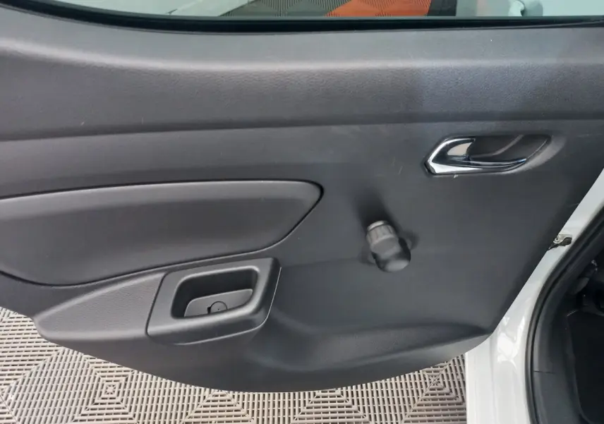 Vue rapprochée de la porte arrière droite noire d'une Nissan Micra blanche, avec poignée chromée et manivelle de vitre.