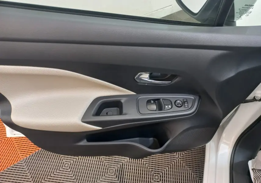 Vue intérieure de la porte avant gauche blanche de la Nissan Micra IG-T 90 Business Edition avec commandes électriques et poignée chrome.