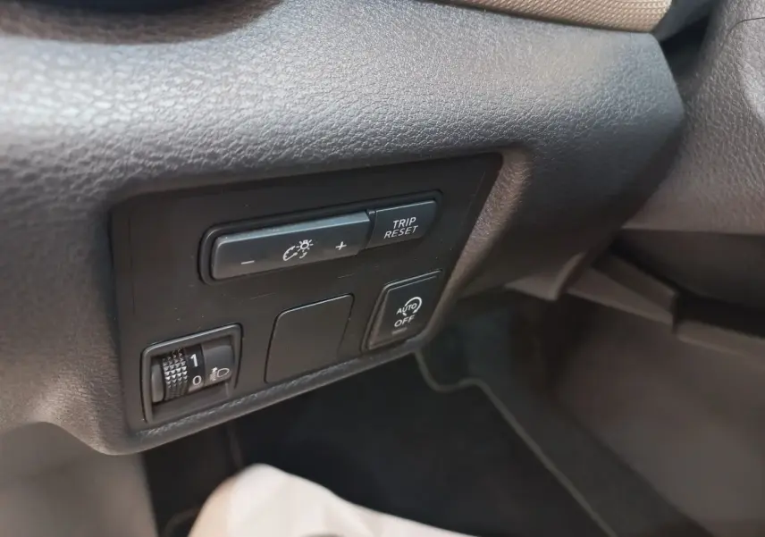 Gros plan sur les commandes de réglage d’éclairage et trip reset dans l’habitacle noir de la Nissan Micra blanche.