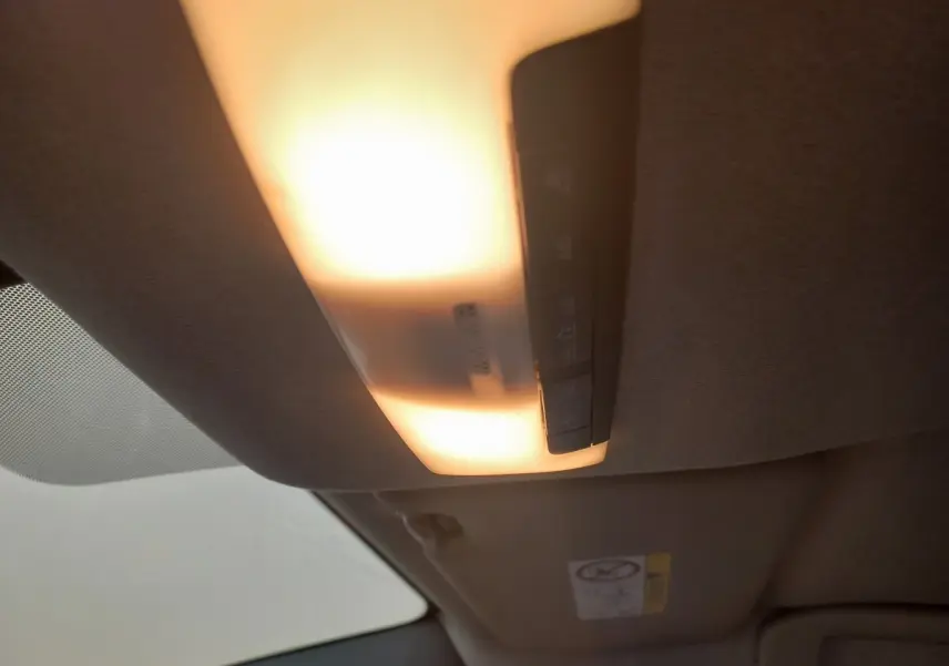 Plafonnier intérieur allumé vu de dessous dans une Nissan Micra blanche, version IG-T 90 Business Edition.