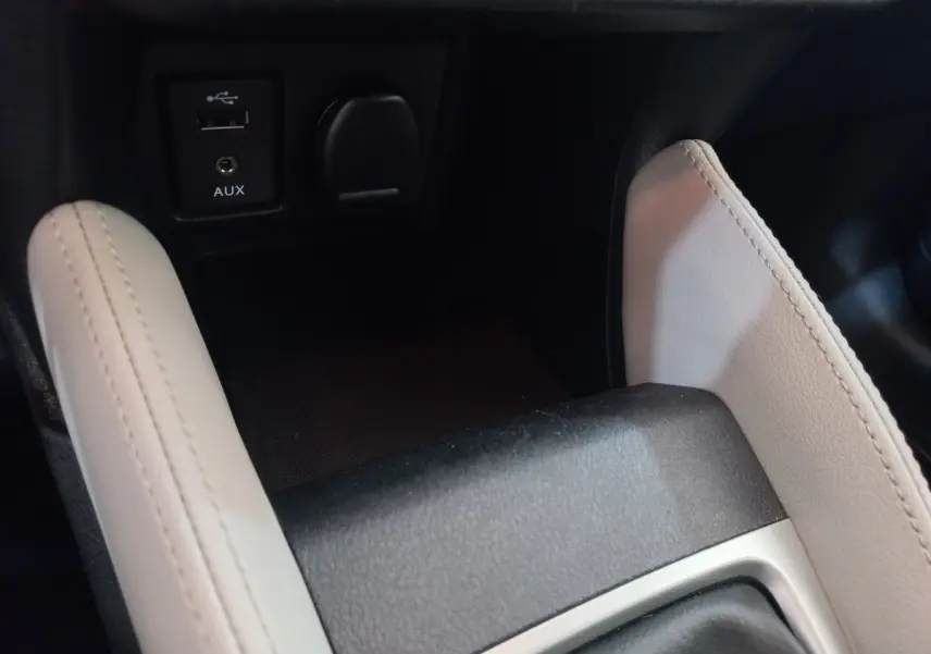 Gros plan sur la console centrale noire et beige de la Nissan Micra IG-T 90 Business Edition avec prise USB et AUX.