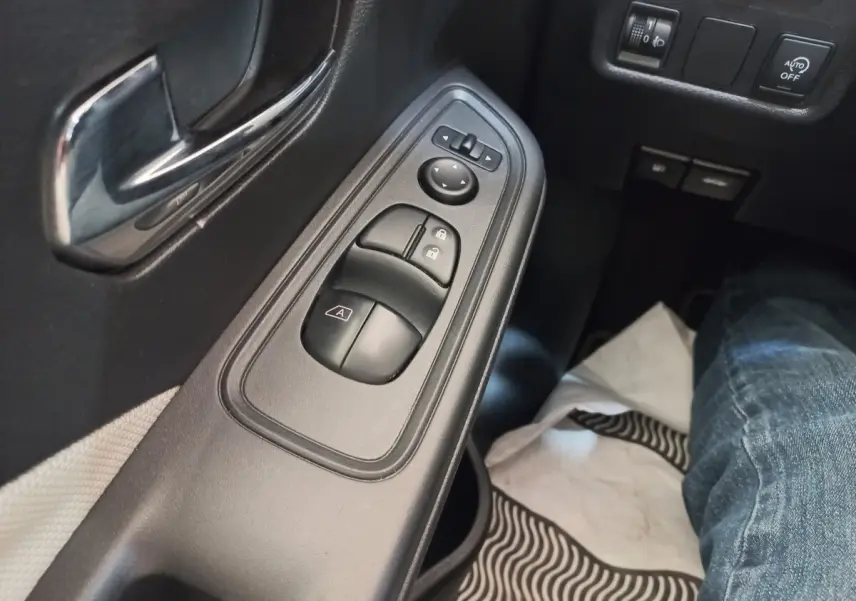 Gros plan sur la commande des vitres et rétroviseurs côté conducteur de la Nissan Micra IG-T 90 Business Edition, intérieur noir.