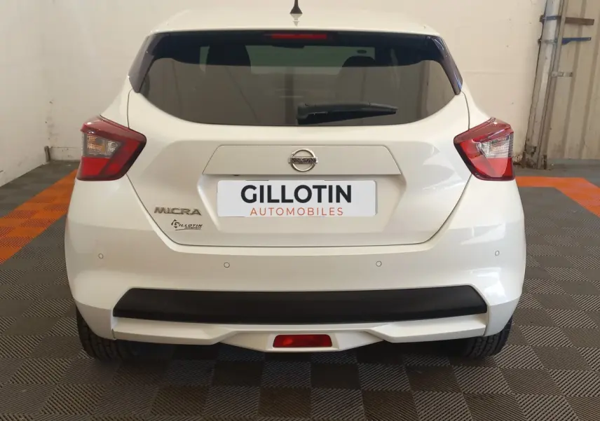 Vue arrière d'une Nissan Micra blanche 2018 avec feux arrière anguleux et pare-chocs noir mat.