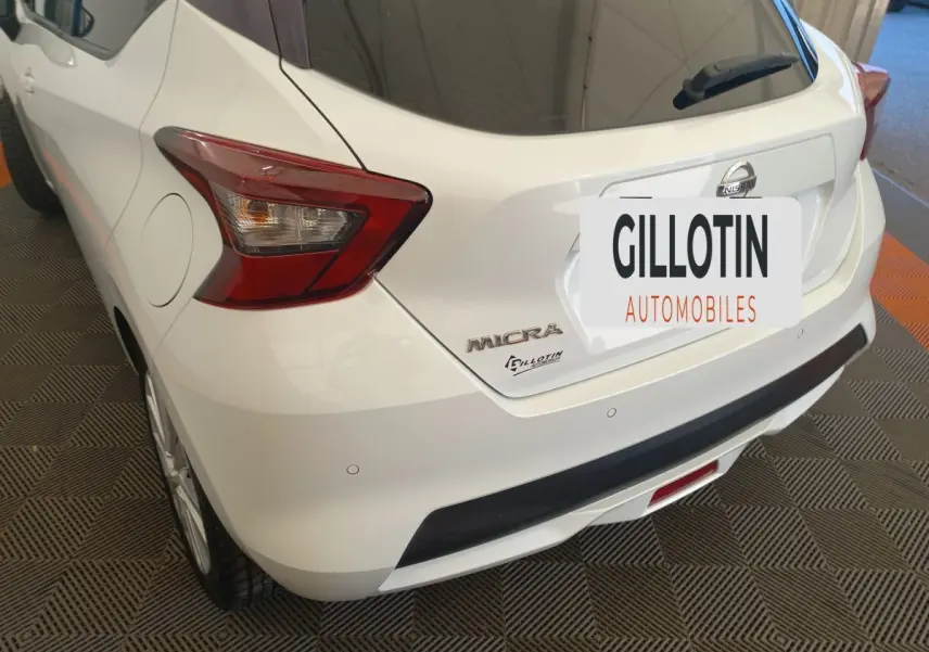 Vue 3/4 arrière droite d'une Nissan Micra blanche avec feux arrière anguleux et logo visible sur hayon.