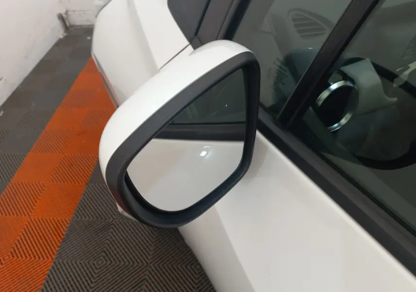 Rétroviseur extérieur droit blanc de Nissan Micra IG-T 90 Business Edition 2018, vue rapprochée sur fond de sol orange et gris.