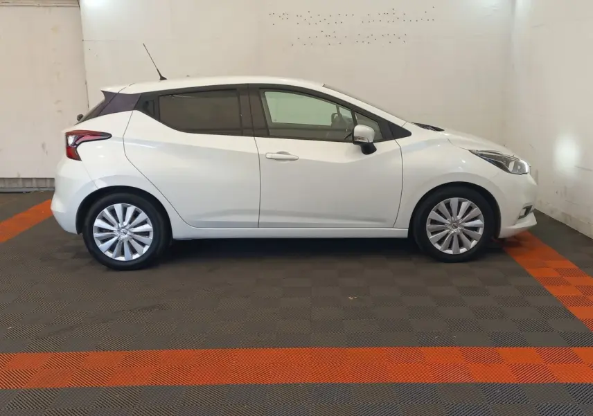 Profil droit d'une Nissan Micra blanche 2018 avec jantes alliage et vitres teintées, stationnée en intérieur.