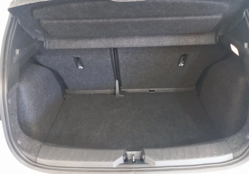 Coffre ouvert vu de face de la Nissan Micra blanche, montrant l'espace de chargement avec banquette arrière rabattue.