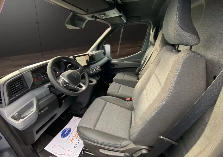 Vue intérieure côté conducteur du Renault Master 2025, montrant les sièges gris et le tableau de bord moderne avec écran tactile.