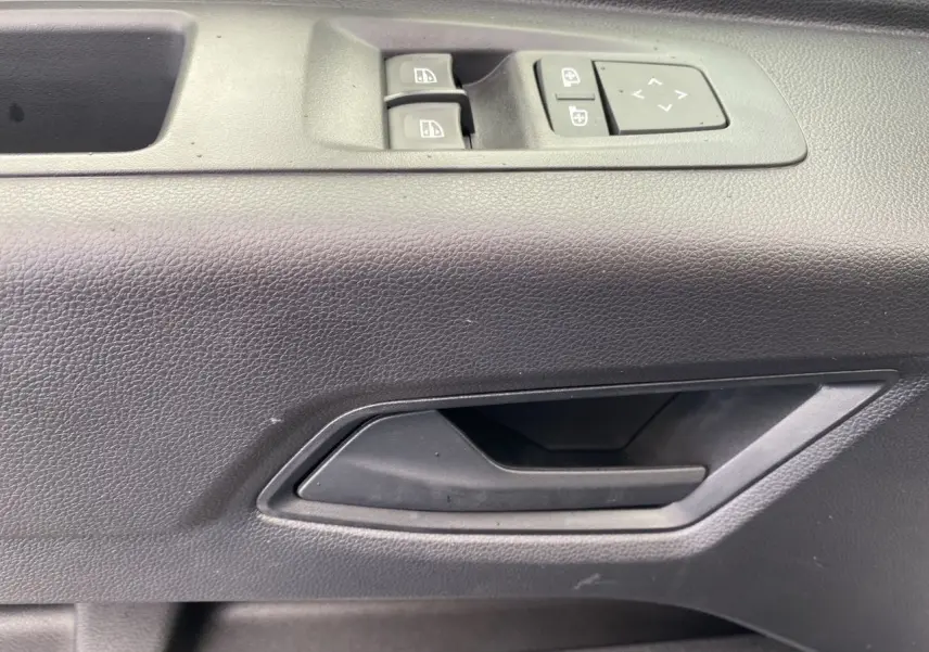 Détail de la poignée intérieure et des commandes de vitre côté conducteur du Renault Master gris urbain 2025.