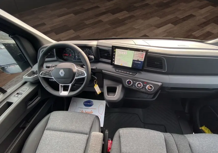 Vue intérieure du poste de conduite du Renault Master 2025, avec tableau de bord moderne et sièges gris urbain.