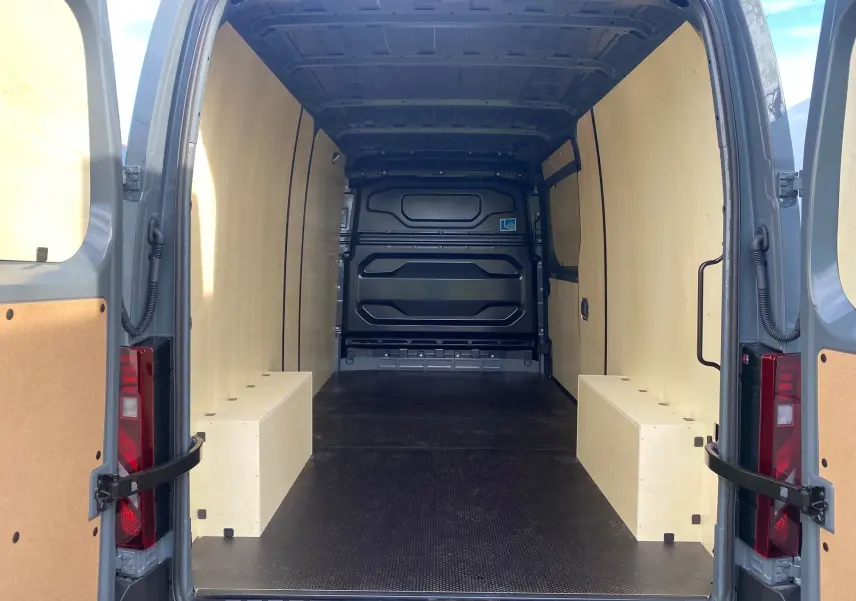Vue arrière ouverte du Renault Master gris urbain 2025, montrant l’intérieur utilitaire avec kit bois et sol noir antidérapant.