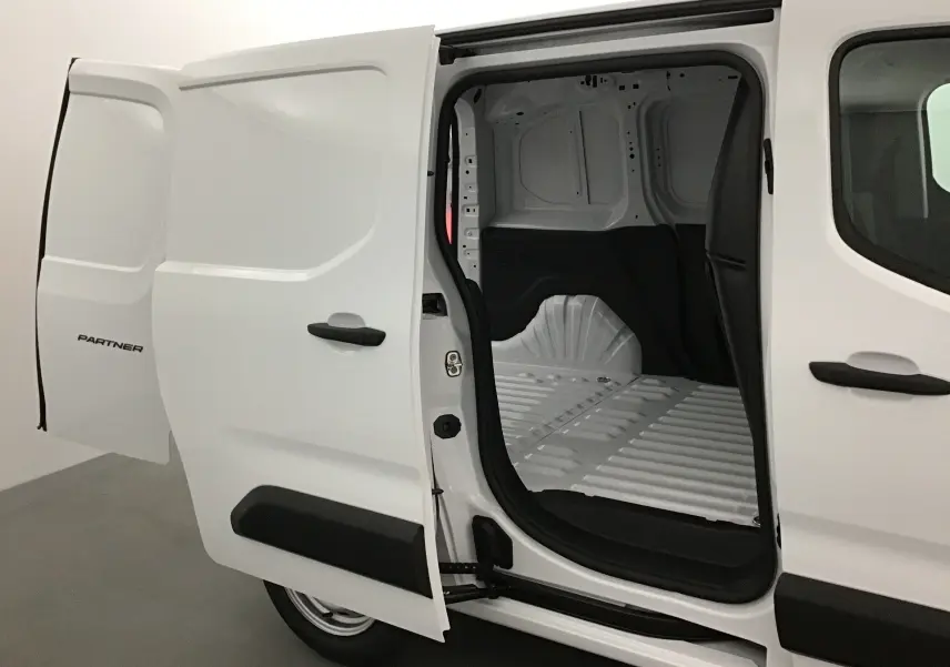 Vue latérale gauche d’un Peugeot Partner blanc 2025 avec porte coulissante ouverte montrant l’espace de chargement vide.