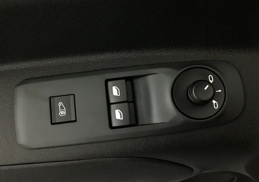 Gros plan sur les commandes de réglage des rétroviseurs et des vitres électriques côté conducteur d’un Peugeot Partner blanc 2025.
