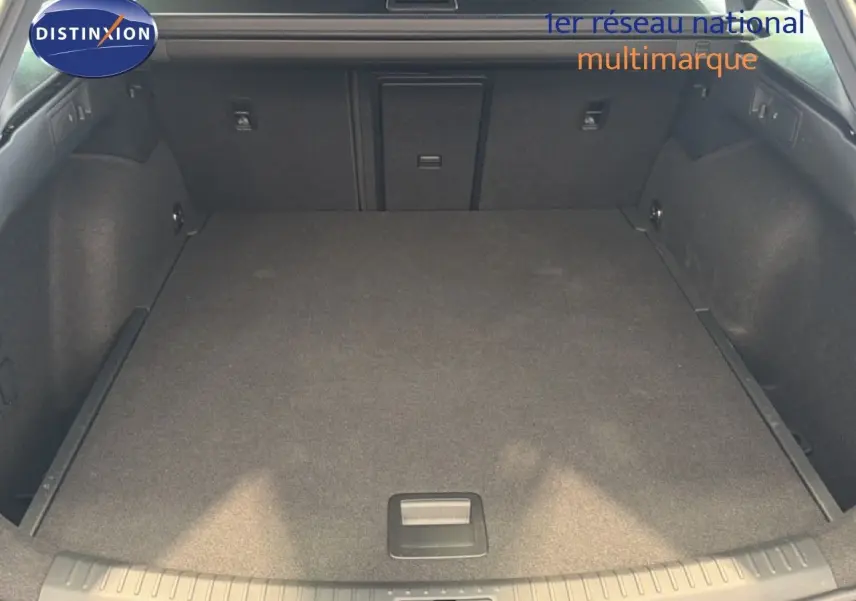 Vue du coffre spacieux et plat de la CUPRA LEON ST 1.5 eTSI en gris magnétique métal, intérieur sombre et propre.