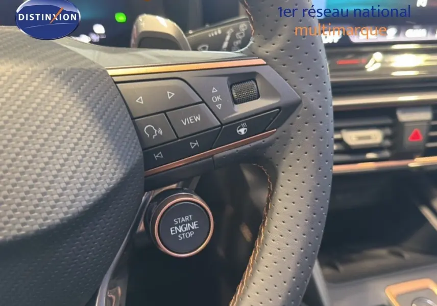 Gros plan sur le volant perforé gris avec commandes intégrées et bouton start/stop de la CUPRA LEON ST 2025.