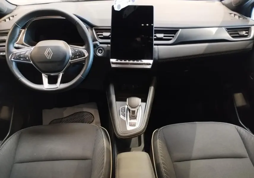 Intérieur avant du Renault Symbioz gris Cassiopée, tableau de bord moderne avec écran tactile vertical et volant multifonction.